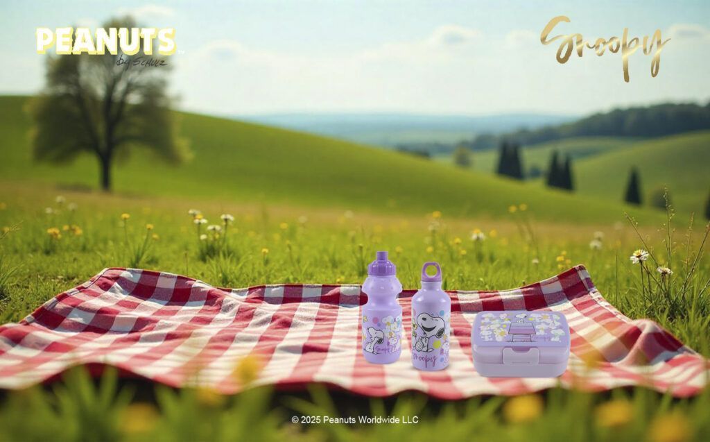 Bodegón de Menaje de Snoopy sobre una manta de picnic de cuadros en un día soleado en el campo. 